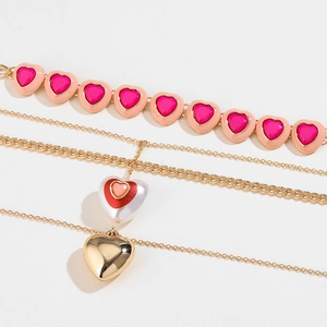 Layered gold necklaces with pink and red heart pendants and chunky curb chain