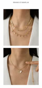 Detail of layered gold alphabet necklace and textured broken heart pendant jewelry