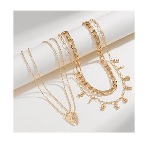 Detailed macro view of layered gold necklaces featuring LOVE heart and BRIDE charms