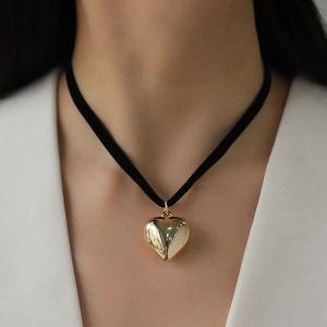 Elegante ciondolo a cuore dorato su una collana choker nera abbinata a un top bianco