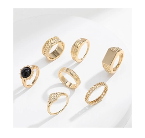 Detail of 7-piece gold fashion ring set featuring black gemstone and textured bands