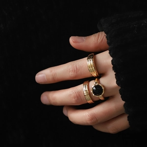 Three-piece gold-plated ring set with a black round stone and ribbed bands on hand