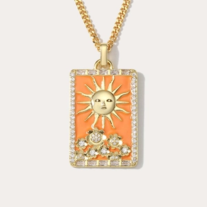 Macro detail of golden sun tarot pendant with orange enamel and crystal border