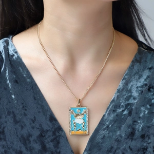 Detail of gold tarot lovers pendant with blue enamel and crystal inlay on necklace