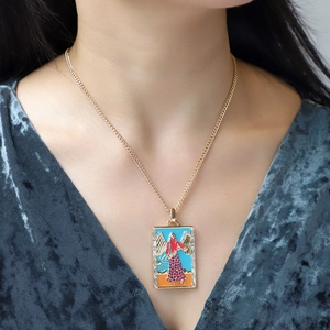 Macro shot of tarot pendant necklace with enamel angel and zircon frame on a model
