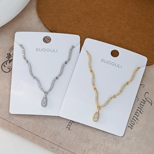 Detail van golvende kristallen chokers met druppelvormige hangers in goud en zilver