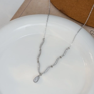Detailweergave van zilverkleurige druppelhanger met zirkoonstenen aan een fijne ketting