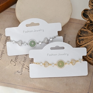 Détail de bracelets cœur dorés et argentés avec pierres vertes sur présentoir