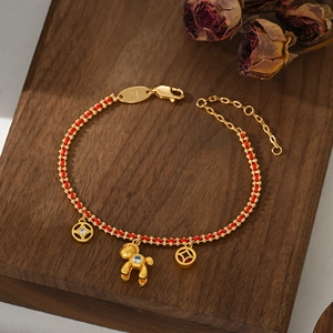 Macro detail of red woven bracelet with gold horse charm and gemstone coin pendants