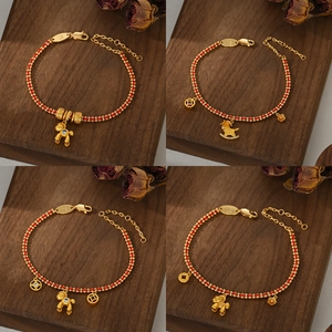 Golden red string bracelets set with horse and bear charms on a dark wood background