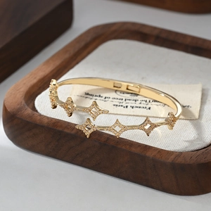 Close-up of a gold star-shaped bangle with micro-pave zircon on a rustic wooden background