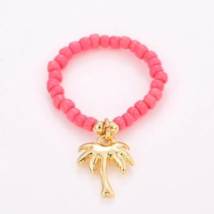 Detailed view of pink beaded summer ring with a golden palm tree charm pendant