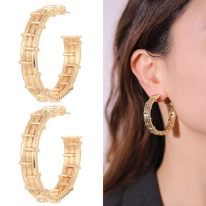 Vista macro di grandi orecchini a cerchio dorati con un esclusivo design a coste multistrato