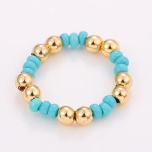 Close-up of handmade beaded ring with gold metallic balls and turquoise blue beads