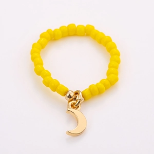 Detailed shot of handmade yellow seed bead elastic ring with a gold moon charm