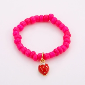 Macro detail of a rose pink beaded bracelet featuring a strawberry-shaped metal pendant charm