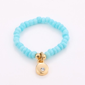 Detail of light blue beaded ring featuring a gold round pendant with clear zircon stone