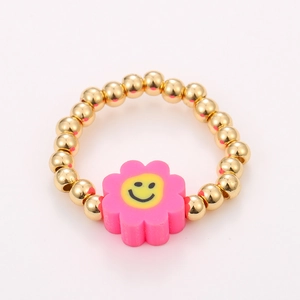 Detail of pink flower charm with yellow smiley face on golden beaded elastic ring