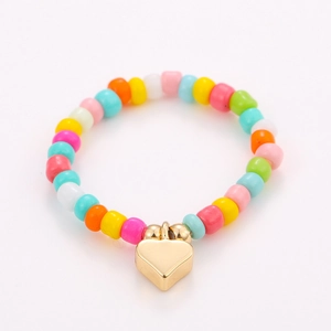 Detailed close-up of colorful seed bead ring set with a golden heart charm