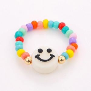 Detail of handmade colorful beaded ring with a white smiley face charm on a white background