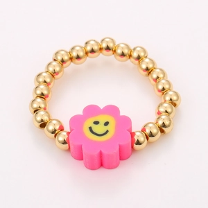 Detail of colorful beaded elastic rings set with pink smiley face flower charm and gold beads