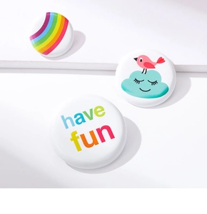 Detailed view of 3-piece colorful enamel badges featuring rainbow, bird and have fun slogan