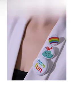 Close-up of three colorful round enamel pins with rainbow and bird on white blazer lapel