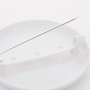 Back view of a white round enamel brooch with secure metal pin and safety clasp lock