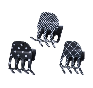 Gros plan de trois pinces à cheveux noir et blanc avec pois et motifs géométriques