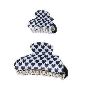 Detail of two black and white heart pattern acrylic claw clips in small and large sizes
