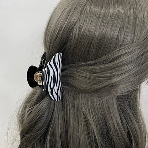 Elegant zebra print hair claw clip with black and white patterns and gold metal hinge