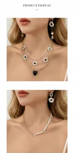 Dettaglio di collana di perle multistrato con ciondoli a cuore nero e fiori