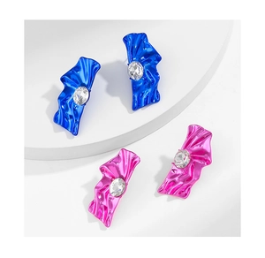 Macro detail of metallic cyberpunk earrings in rose pink and electric blue with crystals