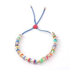 Detail of colorful clay beads and white crystals on a blue woven bracelet with red heart