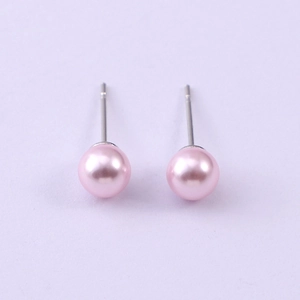 Macro shot of pink round glass pearl studs with silver metal posts on purple background
