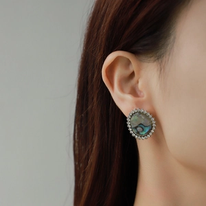 Close-up of model wearing oval earrings with abalone shell inlay and zircon halo