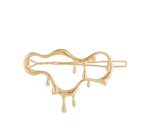 Vue détaillée de la pince à cheveux dorée au design fluide de métal liquide poli