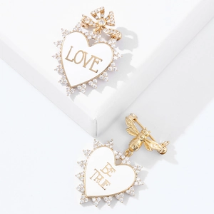 Detailed shot of gold heart brooches with rhinestones and Love or Be True lettering