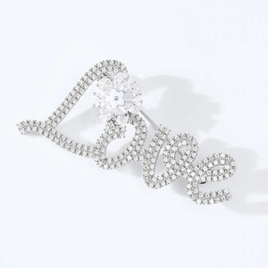 Dettaglio ravvicinato della spilla Love in argento con cristalli pavé e fiore decorativo