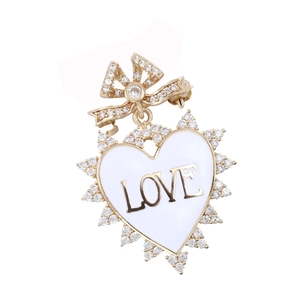 Detailed macro view of heart-shaped brooch with LOVE engraving and crystal bow