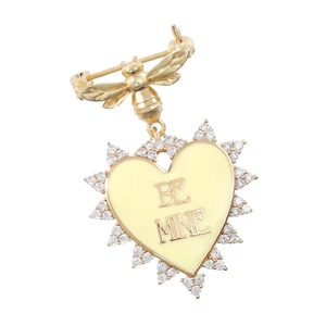 Detailed macro view of heart-shaped brooch with golden bee and Be Mine engraving