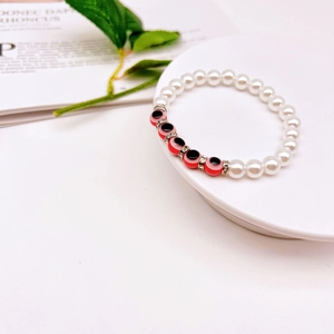 Detailed close-up of baroque pearl bracelet with red evil eye beads and crystal spacers