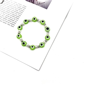 Dettaglio braccialetto di perle occhio del male verde con accenti argento su rivista