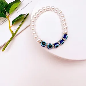 Detail view of Baroque pearl bracelet featuring blue evil eye glass beads and rhinestones