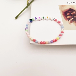 Détail du bracelet en perles colorées avec lettres BEST et breloque œil de protection