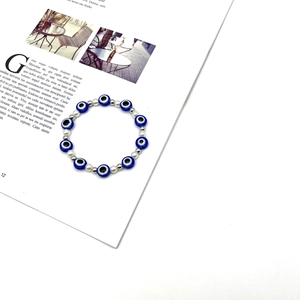 Dettagli delle perline evil eye e perle bianche su un bracciale elastico
