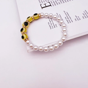 Close-up of beaded evil eye bracelet featuring white baroque pearls and gold spacers