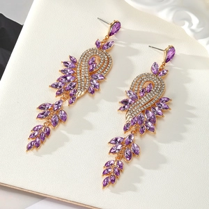 Detailed close-up of luxury long drop earrings with purple crystals and gold leaves