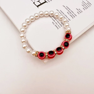 Macro detail of Baroque pearl bracelet with Evil Eye beads and gold crystal spacers