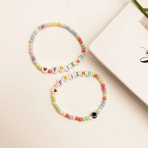 Gros plan de bracelets d'amitié bohèmes colorés avec lettres FRIEND et breloque œil de protection